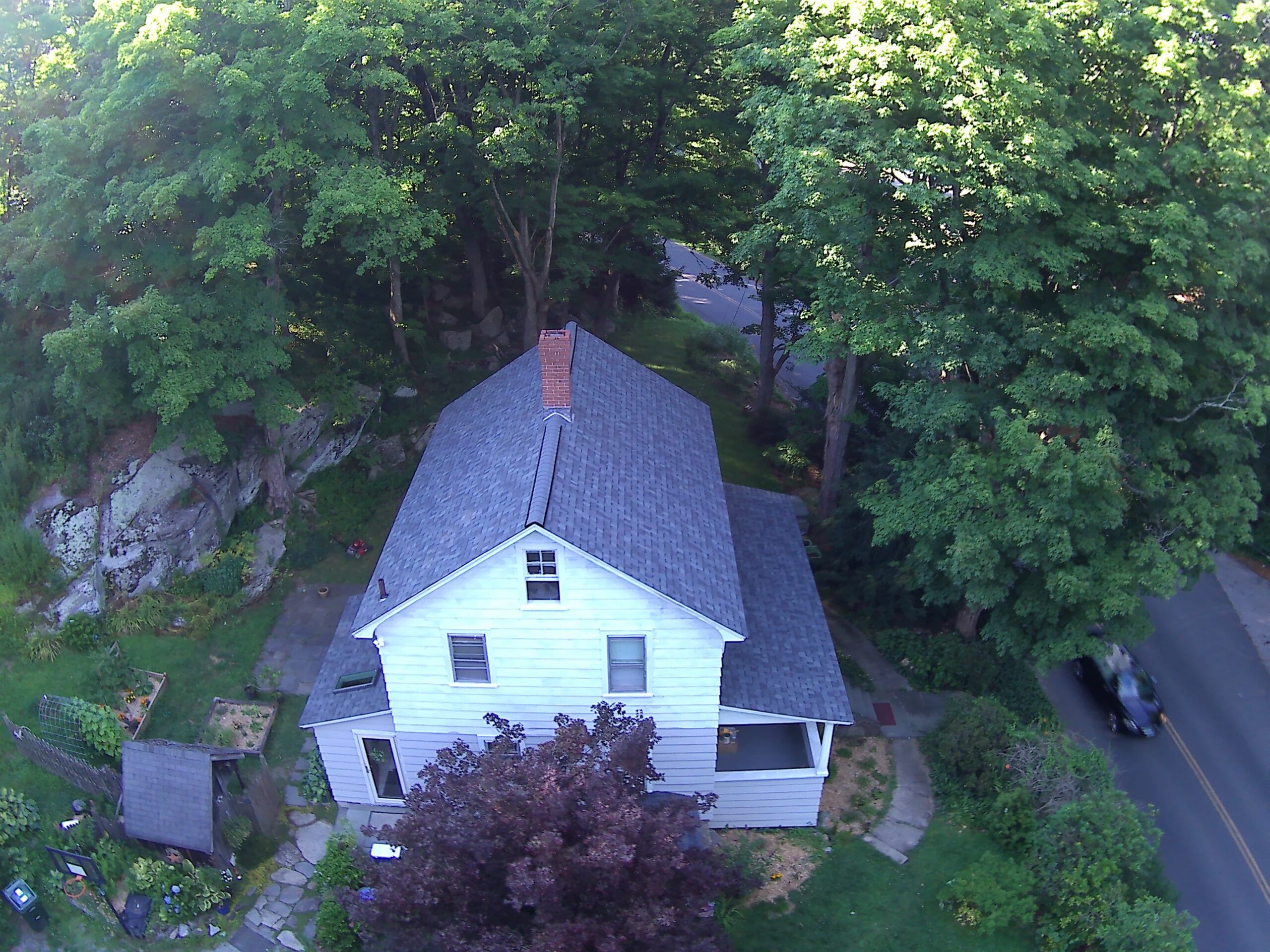 Aerial view of an A-frame Connecticut home with a finished roof surrounded by trees
