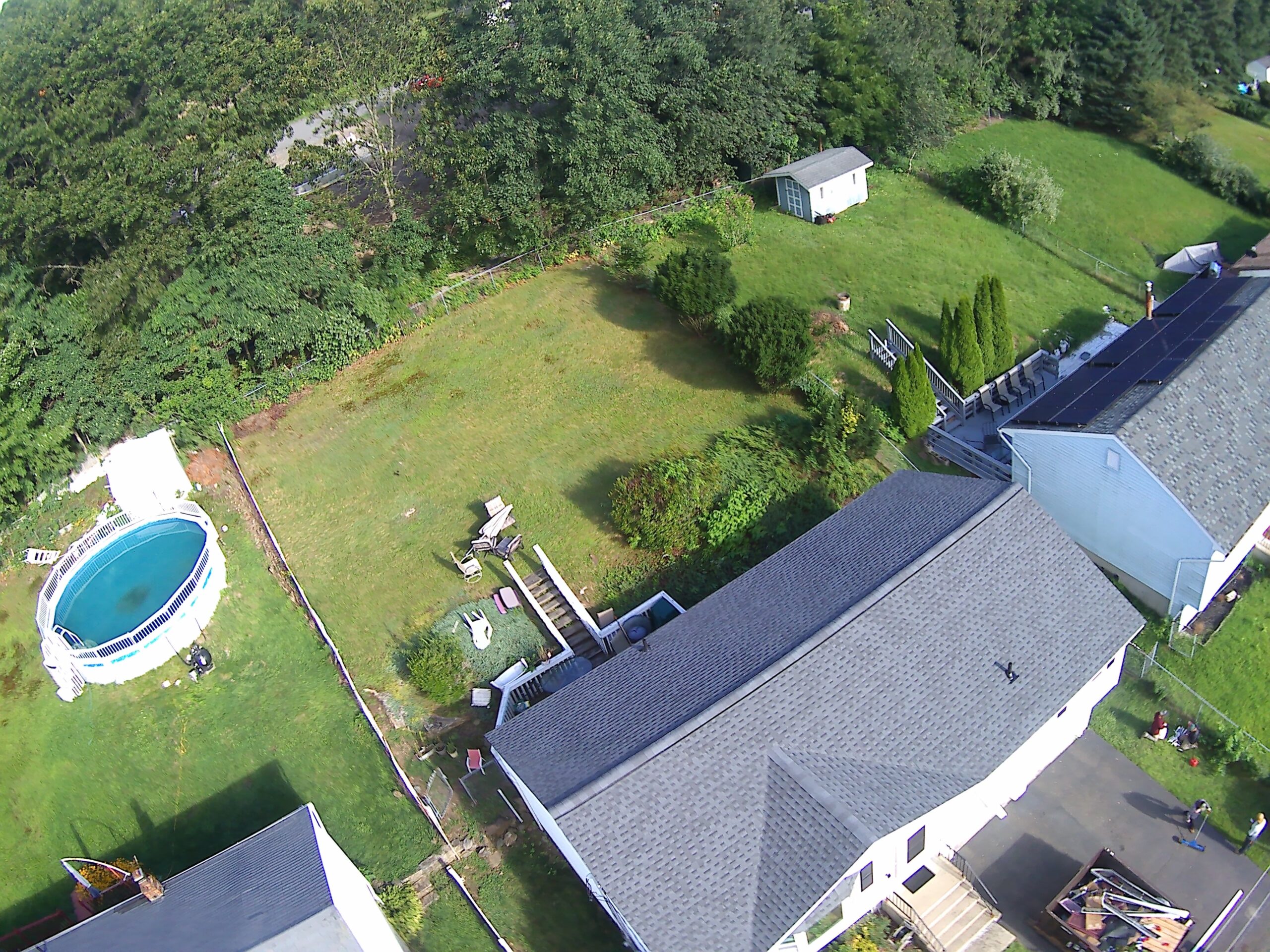 Aerial drone view of a Connecticut home with a freshly finished roof, green lawn and mature trees — an Everett Construction project