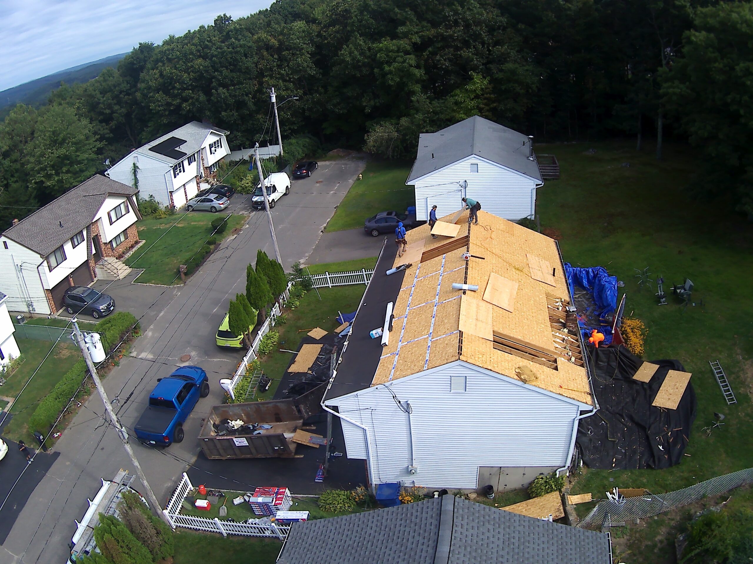 Aerial view of a home with a new roof, deck and pool surrounded by green lawn