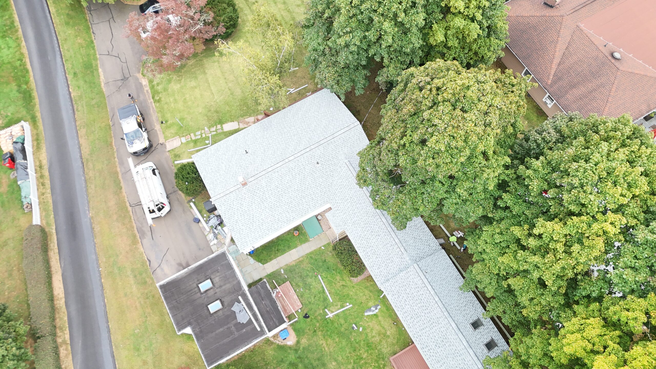Aerial view of a completed residential roof framed by mature trees