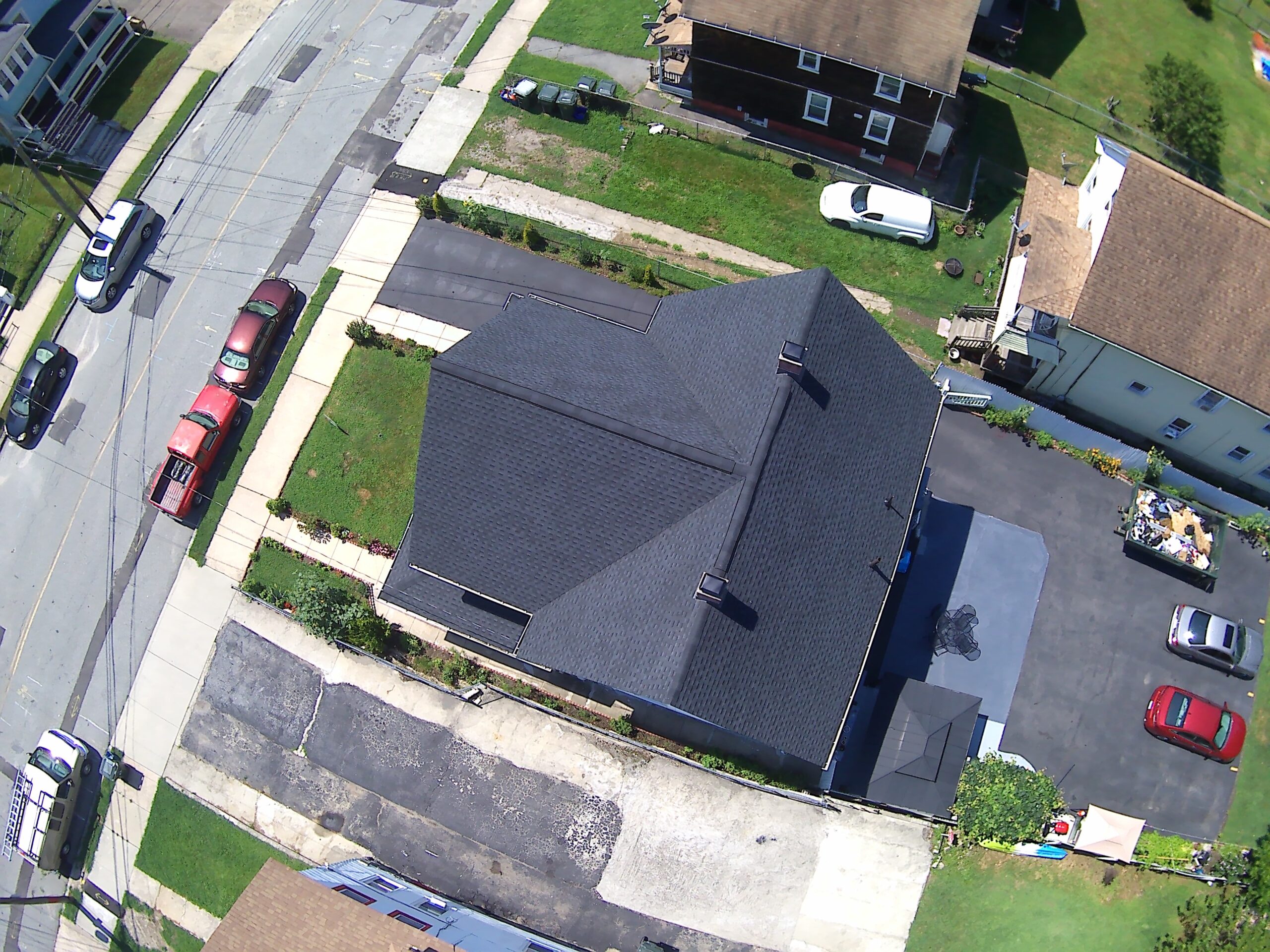 Aerial view of a white A-frame home with a new roof set among green trees