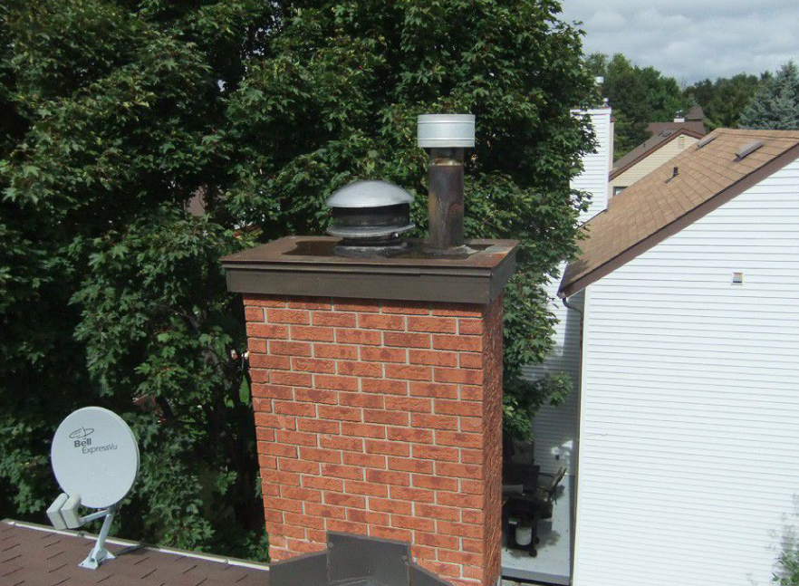 Brick chimney rising above a white home’s roofline